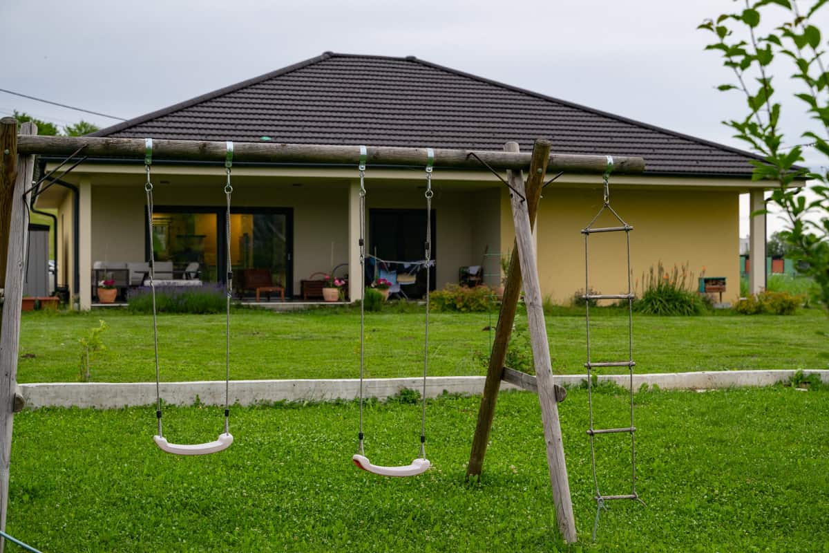 Leere Kinderschaukel im Garten vor einem Einfamilienhaus